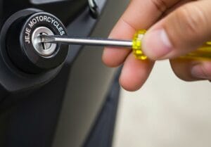 Person jamming a screw driver into a motorcycle lock