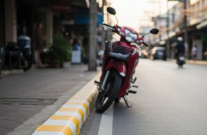 Scooter in Thailand parked up against yellow and white curb