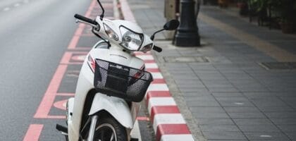 Scooter parked in a no parking zone, indicated by red and white curb